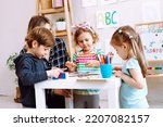 English teacher with children have fun and playing games, learning alphabet and numbers by arts in kid development childcare center. Daycare and babysitting. English school, study british and american