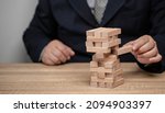 Small photo of Business risks, job instability, the collapse of mind, businessman pulls puzzle sticks out of a group full of risks of falling.