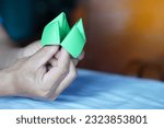 Closeup hands hold green origami paper fortune teller. Concept , Life opportunity. Paper toy that can use as creative game in summer camp or classroom activity for fun.                        