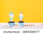 Small photo of 90 number candle on a cup cake with colorful sprinkles and yellow background ninetieth birthday anniversary celebrations