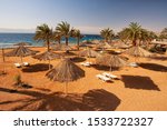 Small photo of Aqaba beach with sunshades and deckchairs.