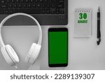 Small photo of calendar date on a light background of a desktop and a phone with a green screen. August 30 is the thirtieth day of the month.