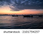 Beautiful scene of seascape after the sunset time. Very nice dark clouds with the a silhouette of a long tail boats in the background.