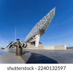Small photo of Antwerp Belgium 13 November 2022: The Port Authority Building (Havenhuis), or the Port House, designed by architect Zaha Hadid against a blue sky and iron hand on bitts, an artwork of Bruno Kristo