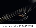 low-key photo of a fragment of a black guitar against a dark background. guitar music photo aesthetic