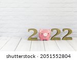 2022 new year and  piggy bank on white wood table over white background with copy space , saving concept
