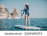 Woman sup yoga. Middle age sporty woman practising yoga pilates on paddle sup surfboard. Female stretching doing workout on sea water. Modern individual female hipster outdoor summer sport activity.