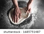 The process of preparing pizza, a person rolls out the dough with his hands. Horizontally close up.