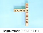Small photo of Abstract nouns concept in English grammar noun education. Wooden block crossword puzzle flat lay in blue background.