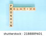 Small photo of Relative pronoun concept in English grammar education. Wooden block crossword puzzle flat lay in blue background.