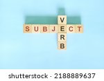 Small photo of Subject verb agreement concept in English grammar education. Wooden block crossword puzzle flat lay in blue background