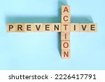 Small photo of Preventive action business concept. Wooden blocks crossword puzzle flat lay.