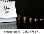 Small photo of Fourth quarter of 2023 negative performance financial report and fiscal concept. Downward arrow with decreasing coins and calendar in black background.