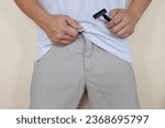 Closeup of male crotch with hand holding a shaver. Shave pubic hair down under concept. Men's Fitness, grooming and health.