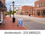 Small photo of Louisburg, North Carolina USA-06 01 2023: Decorative Signs and Red Brick Sidewalks Beautify Downtown Louisburg.