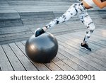 Fitness woman doing exercise with fitness ball on wooden floor. Fitness girl wearing in white trending leggings and top. Close up