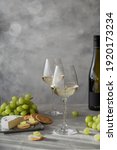 Small photo of Two glass with white wine. Brie and salty biscuits and white grapes. A bottle of white wine. A still lifestyle.