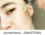 Small photo of Close-up portrait of woman applying glass peep liquid, skin texture. Apply a tea tree moisturizing serum to your face.