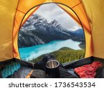 Camping with holding cup in yellow tent open with Peyto Lake in Icefields Parkway at Canada