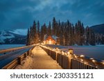 Beautiful view of Emerald Lake with wooden lodge glowing in snowy pine forest on winter at Yoho national park, Alberta, Canada