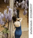 Small photo of a woman in denim dress from behind by blooming flowers near little Marie Antoinette's house