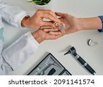 Small photo of Audiologist puts modern BTE hearing aid in patient hand for treatment deafness at hearing clinic, top view. Hearing solutions