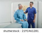 Small photo of Radiographer talking with male patient in hospital radiology department prior to CT scan being performed. Computed Tomography