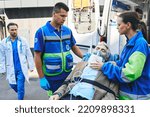 Small photo of Doctor rushing to senior patient with breathing mask on ambulance stretcher who was brought by paramedics in ambulance. EMS