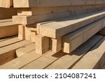 Wooden building materials close up.
A stack of natural wooden boards at a construction site. Industrial edged timber. Wooden rafters for renovation or construction. Roofing and carpentry lumber.