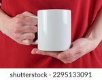 Small photo of Closeup of woman's hands holding a blank 11 oz. white coffee mug. Her red blouse adds pizazz to the background.