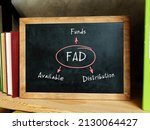 Small photo of FAD Funds Available Distribution on Concept photo. Blank small blackboard and different school stationery on wooden table near white wall.