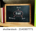 Small photo of Written phrase BMR Basal Metabolic Rate . Bookshelf with multicolor books and chalkboard