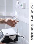 Small photo of Solution for infusion in plastic bag. Medical professional prepares a dropper. Intravenous drip of drugs. Hands in protective gloves. Beyond recognition. Copy space.