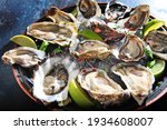 Fresh oysters with lime on a round plate. Oyster season. Macro-seafood dish. Oyster on the half shell.Two varieties of oysters.Out of focus.