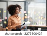 Small photo of African American female employee write down on colorful sticky notes manage list, concentrated biracial woman work on startup brainstorm collaborate plan on stickers on glass wall