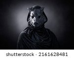 Small photo of Black wolf in hooded cloak at night over dark misty background