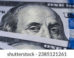 Small photo of Benjamin Franklin's eyes from a hundred-dollar bill. The eyes of Benjamin Franklin on the hundred dollar banknote, backgrounds, close-up. 100 dollar bill with only eyes of Benjamin Franklin