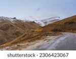 Snow covered mountains, cloudy sky, the road at Tanglang La Pass, elevation 5,328 metres (17,480 ft), is a high altitude mountain pass in the Indian union territory of Ladakh. 
