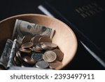 Small photo of One tenth or tithe is basis on which Bible teaches us to give one tenth of first fruit to God. coins with Holy Bible. Biblical concept of Christian offering, generosity, and giving tithes in church.