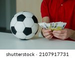 Small photo of Lucky man with soccer ball counting euro banknotes. Close up of male hands count money cash payout after win at football betting. Concept of betting, gambling.