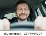 Close up portrait of happy excited driver begginer behind the wheel of his first car.