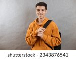 Small photo of Portrait of a young student with a school bag. The teenager smiles and looks at the camera. A happy teenage boy on a grey background