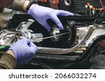 Small photo of A mechanic wearing rubber gloves installs an LED lens into the headlight housing.Car headlight during repair and cleaning.The mechanic restores the headlight of the car.Restoration of automotive optic