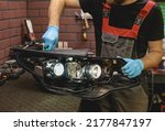 Small photo of Car headlight in repair close-up. The car mechanic installs the lens in the headlight housing. The concept of a car service.Installation of LED lenses in the headlight. LED lens.Restoration of optics.
