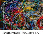 Small photo of Colored telecommunication cables and wires tangled in a tangle in a box. The multicolored wires and cables in the box are mixed up and tangled into knots.