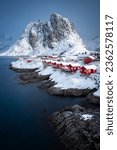 Vertical photo of Hamnoy fishing village in Norway. Lofoten winter scene with typical red houses and a snowy mountain in the background.