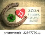 Decoration with four leaf clover horseshoe and heart for New Year 2023 with text in german 2024 FROHES NEUES JAHR 2024 means in english 2024 HAPPY NEW YEAR 
