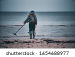 Man with a metal detector on a sea sandy beach.