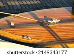 Small photo of Boat at a wooden dock in harbor. Boat knot equipment. Mooring knot, hitch on wooden desk. Yacht detail. Travel and lifestyle view. Rigging equipment. Varnish wooden desk of boat. Landing stage.