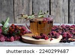 Small photo of A cup of fruit tea with dried berries of hawthorn, sea buckthorn, raspberry, plum, barberry on a wooden vintage background.